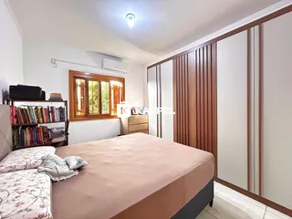 Quarto com cama grande, estante de livros e painéis de madeira em um ambiente interno.