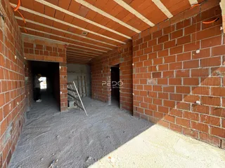 Corredor interno com paredes de tijolo aparente e estrutura de teto de madeira.