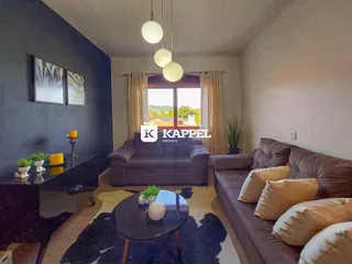 Sala de estar com sofá grande e vista pela janela.