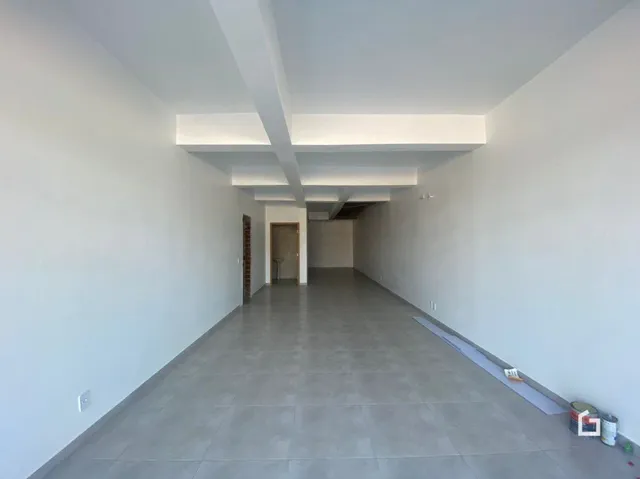 Corredor interno de uma residência com paredes brancas e piso cinza claro.