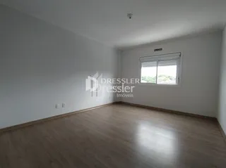 Uma sala com piso de madeira clara e paredes brancas.