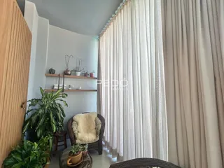 Ambiente interno com cortinas longas e decoração de plantas em um imóvel.