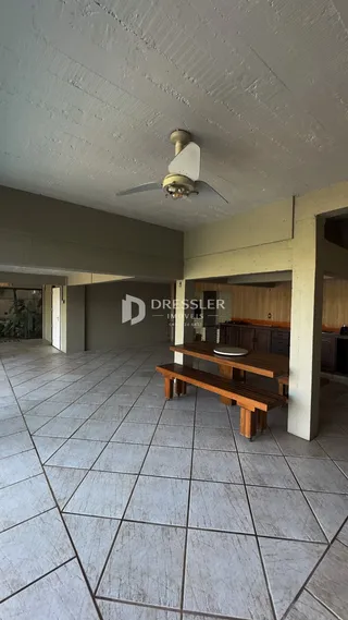 Vista interna de uma área ampla com piso de cerâmica e teto texturizado.