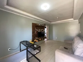 Sala de estar com paredes em tom verde-azulado e piso de cerâmica clara.
