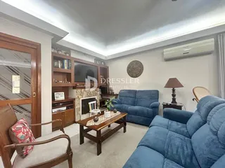 Sala de estar com sofás azuis e móveis de madeira em um imóvel no Brasil.