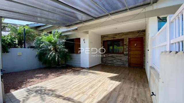 Patio externo de madeira com piso de madeira e vegetação ao lado da casa.