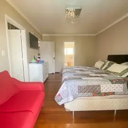 Quarto com cama e piso de madeira clara.