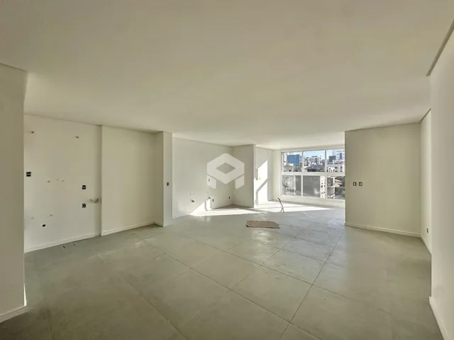 Interior de um espaço vazio com paredes brancas e piso claro.