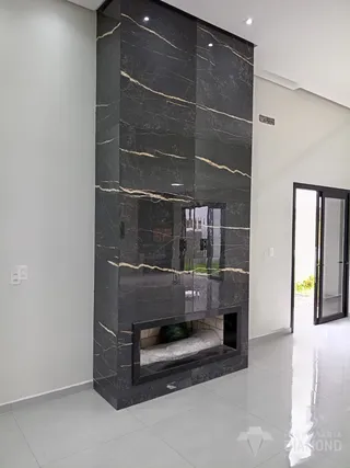 Parede de destaque com revestimento de mármore escuro e lareira em um ambiente interno.