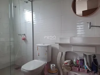 Foto de um banheiro com revestimento cerâmico e box de vidro.