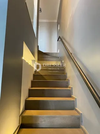 Vista de um corredor com escadaria em uma residência.