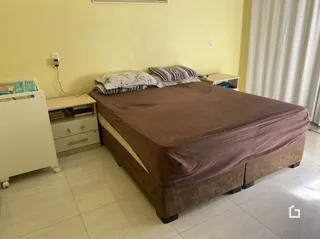 Quarto com cama de casal e paredes amarelas.