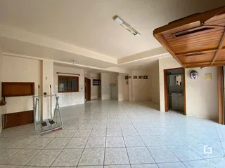 Interior de um espaço amplo com piso de cerâmica e estrutura de madeira.