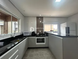 Cozinha moderna com armários brancos e bancadas escuras.