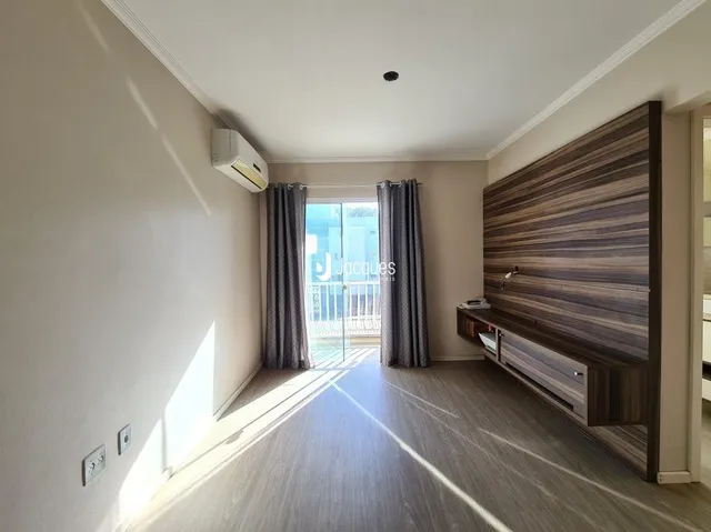 Ambiente interno com piso de madeira e porta de vidro abrindo para o exterior.