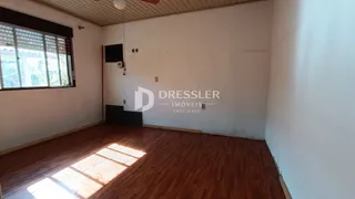 Interior de uma sala com piso de madeira e janela.