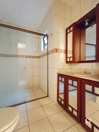 Vista interna de um corredor com paredes brancas e piso de cerâmica.