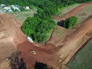 Vista aérea de uma propriedade com áreas de terra e vegetação densa.