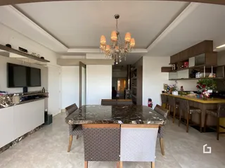 Uma sala de estar com mesa de jantar e lustre de cristal.