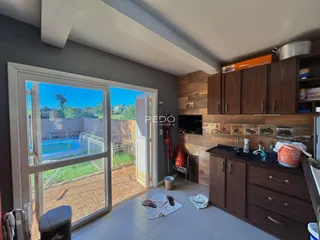 A sala de estar possui portas de vidro que dão acesso a um pátio com piscina.