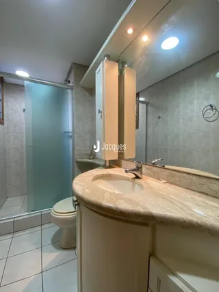 Foto de um banheiro com bancada de mármore e box de vidro.