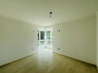 Interior de uma sala ampla com piso de madeira clara.