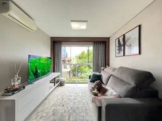 Sala de estar com sofá e televisão voltada para a janela.