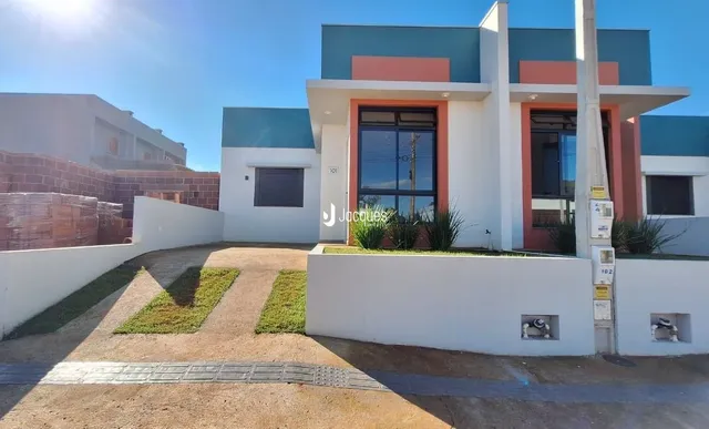 Fachada moderna de uma residência em Lajeado, Brasil, com paredes brancas e detalhes em azul e laranja.