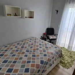 Foto de um quarto com cama coberta.
