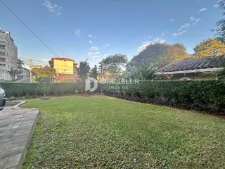 Vista externa de um jardim gramado com cerca viva.