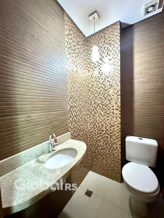 Banheiro com revestimento de azulejos marrons e brancos.