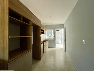 Interior de um corredor com armários de madeira e piso claro.