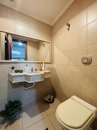 Foto interna de um banheiro com revestimento cerâmico e bancada de mármore claro.