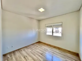 Ambiente interno de uma sala com piso de madeira clara e paredes brancas.