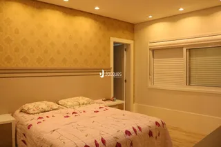 Quarto com cama e parede decorada em tom amarelo.