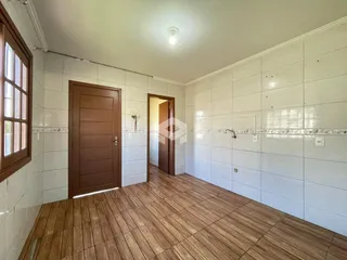 Interior de um corredor com piso de madeira e paredes brancas.