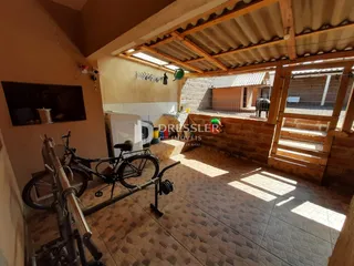 Interior de uma sala com piso de cerâmica e teto de madeira exposta.