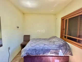 Quarto com cama e janela de madeira.