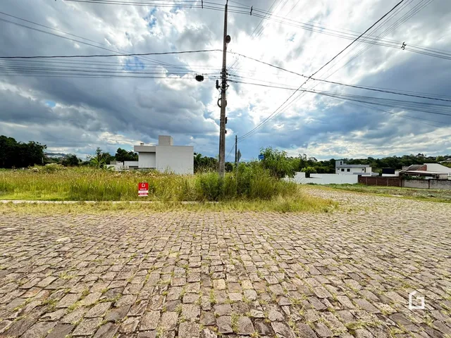 Vista externa de uma propriedade com pavimentação de pedras no primeiro plano.
