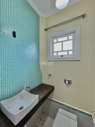 Banheiro com azulejos turquesa e bancada de madeira.