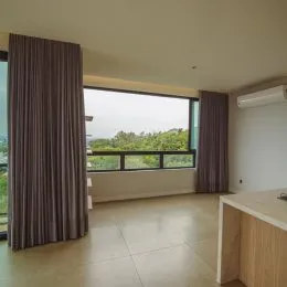 Sala de estar com grandes janelas que dão vista para a vegetação externa.