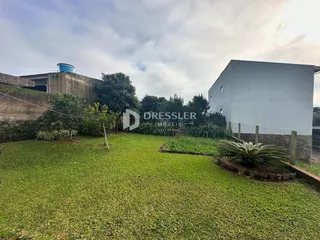 Vista externa de um terreno com gramado e um edifício branco.