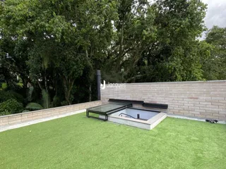 Jardim externo com gramado e área de piscina.
