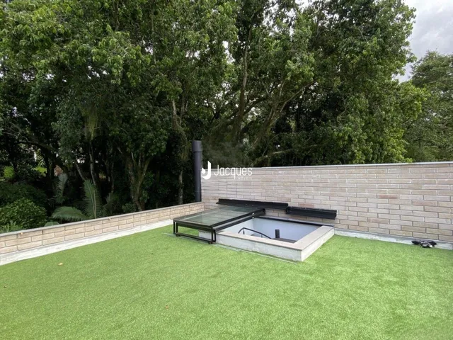 Jardim externo com gramado e área de piscina.