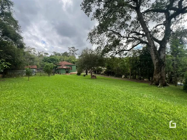 Campo de grama verde com uma residência ao fundo.