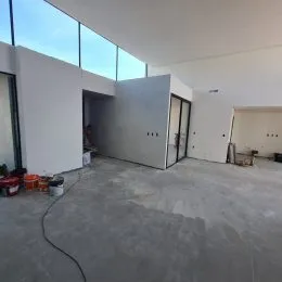 Espaço interno com piso de concreto e grandes janelas de vidro.