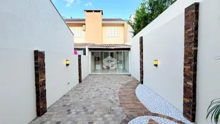 Vista da fachada de uma residência com parede branca e pilares de tijolo aparente.