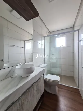Foto interna de um banheiro com revestimento branco e piso de madeira.
