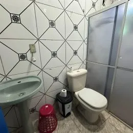 Foto de um banheiro com pia e vaso sanitário revestido de azulejos brancos.