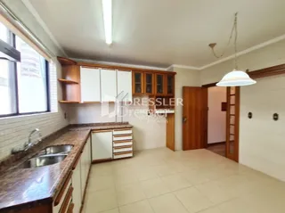 Vista da cozinha com armários de madeira e piso claro.